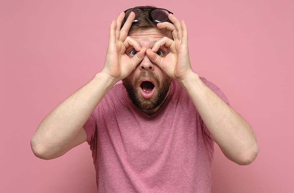 Mann macht eine Suchbewegung als Fernrohr mit den Händen